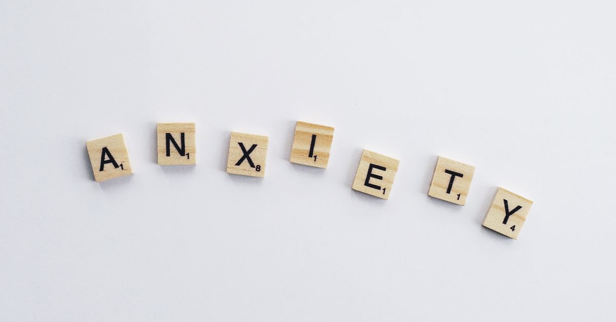 Wooden tiles on a white background spell anxiety, symbolizing mental health awareness.