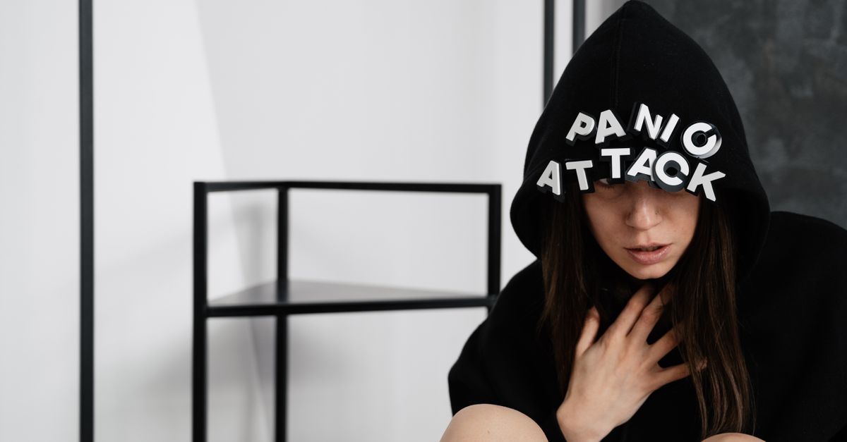 A woman in a hoodie with panic attack letters, representing mental health struggles.