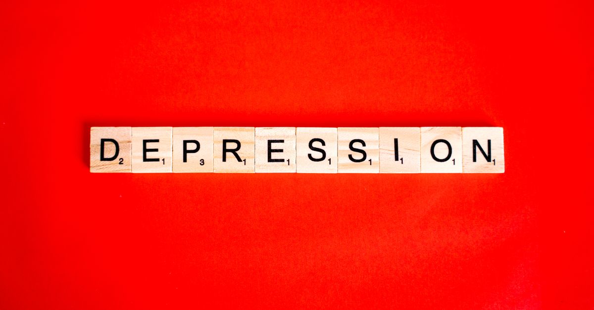 Word depression spelled with letter tiles on vibrant red background, highlighting mental health theme.