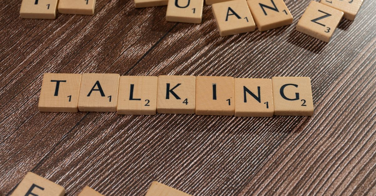 Scrabble tiles spelling 'Talking' on wooden surface, symbolizing communication.