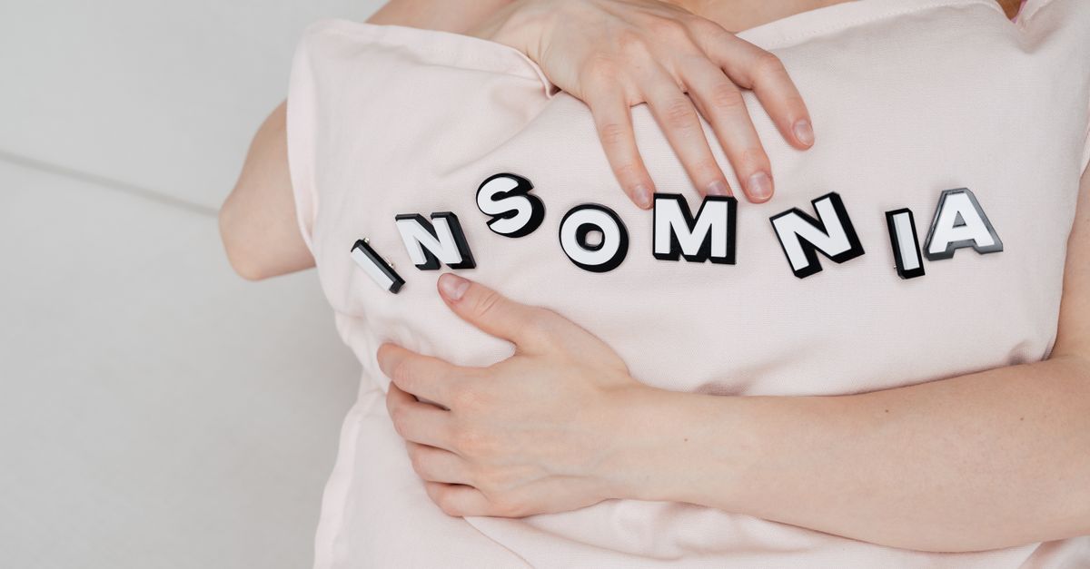 Close-up of a woman holding a pillow with 'insomnia' text, depicting sleep disorder.