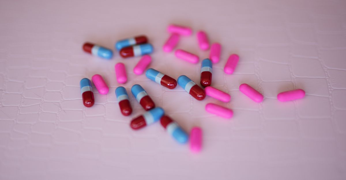Vibrant pink and blue capsules scattered on a light textured background.