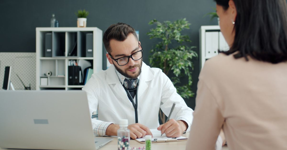 Doctor in white coat consulting patient in a modern office setting.