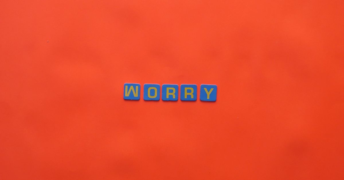 Blue letter blocks spelling 'worry' on a bold orange background. Bright and conceptual design.