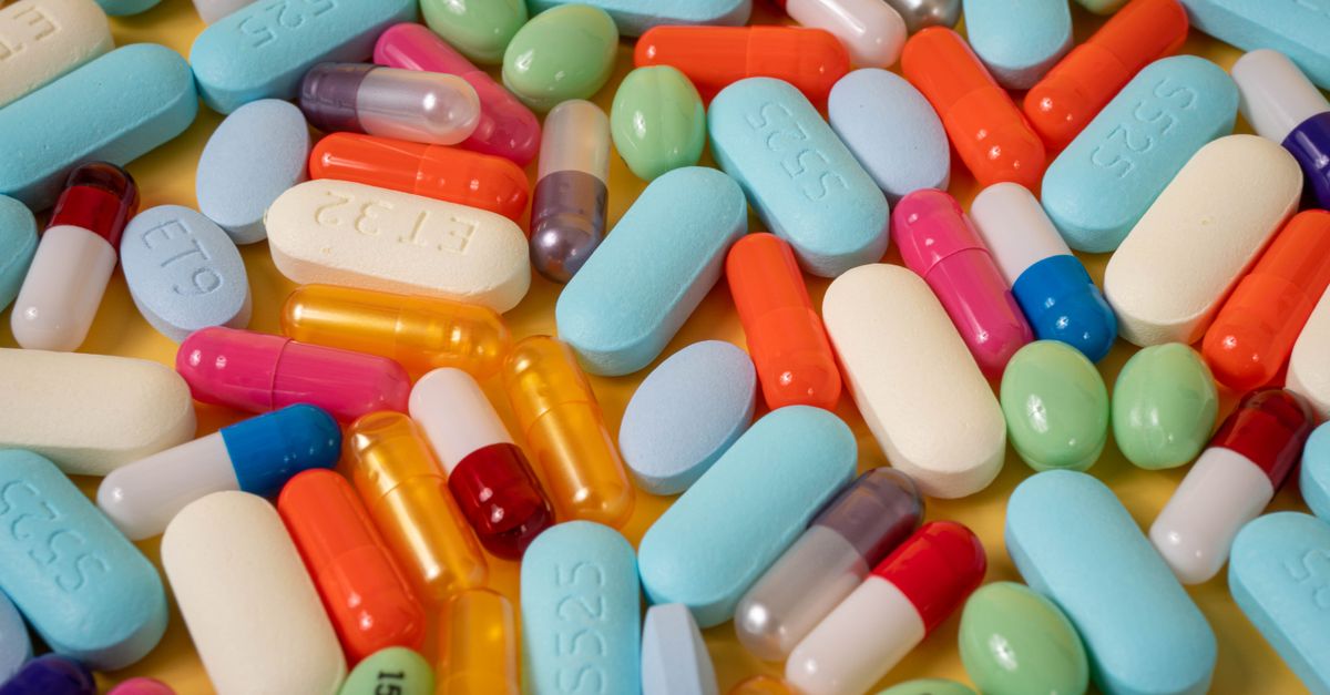 An overhead view of a colorful assortment of pills and capsules on a yellow background.