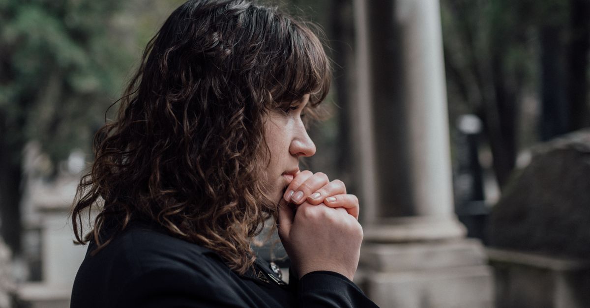 A woman in a cemetery expressing grief and contemplation in a serene outdoor setting.