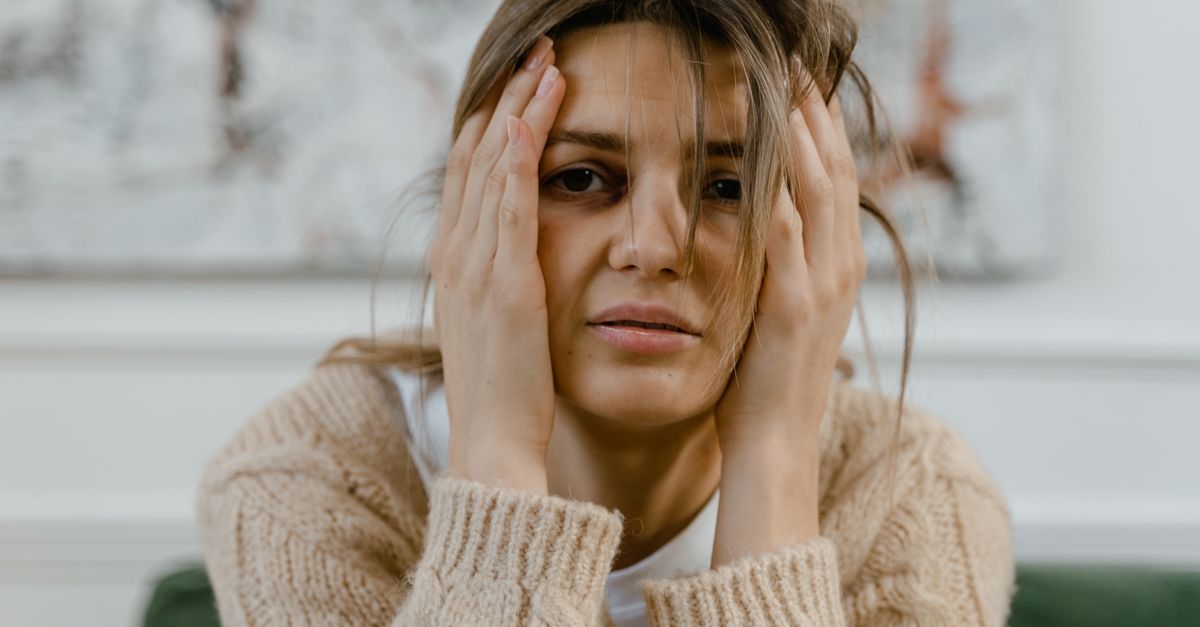 Woman looking distressed with hands on head, expressing worry indoors.